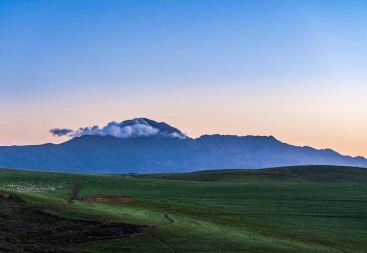 Rolling Farmland Under Mountain Skies